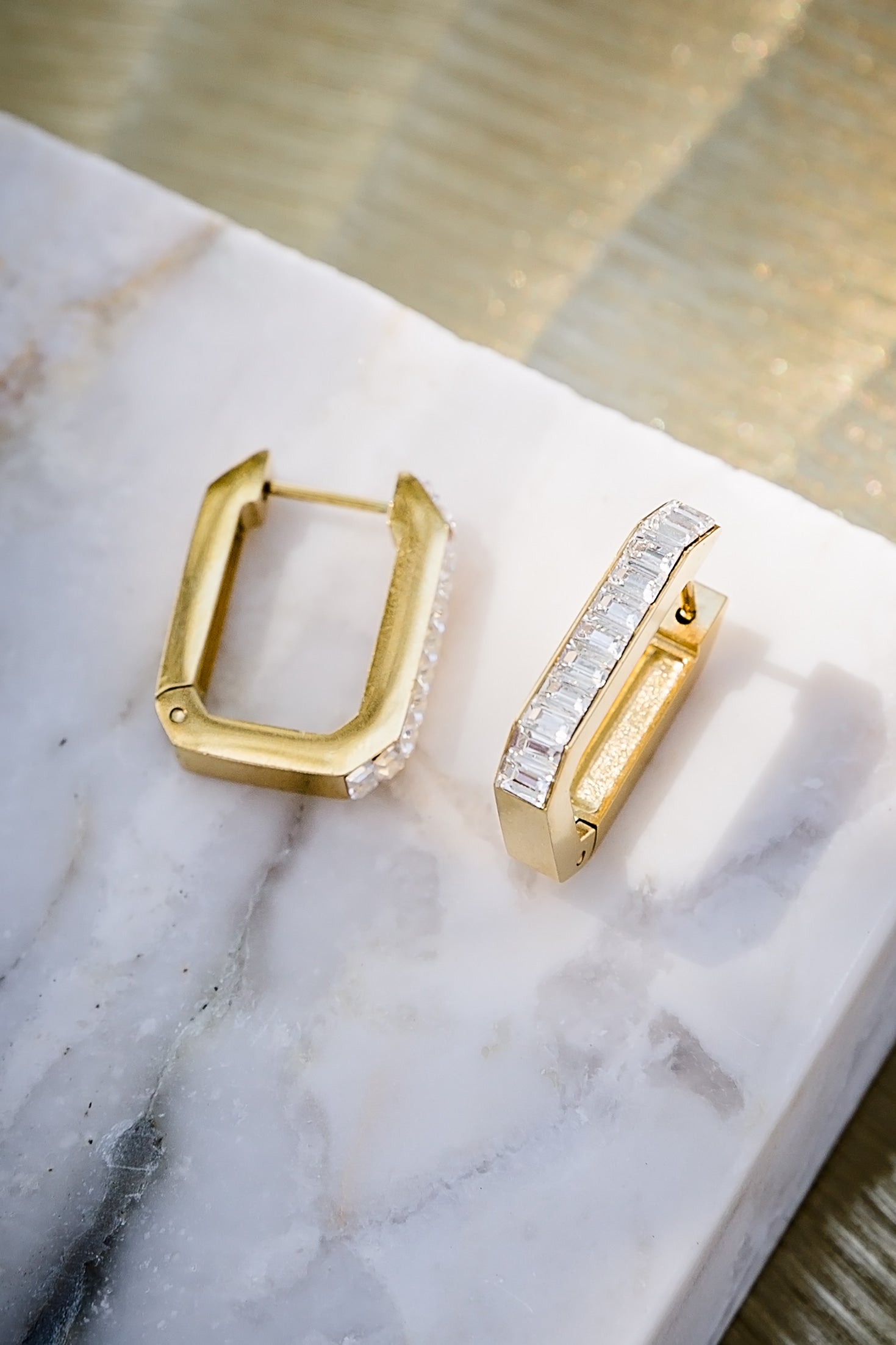 Sloane hoop earrings in gold displayed on marble surface, featuring structured rectangular shape and zircon detailing