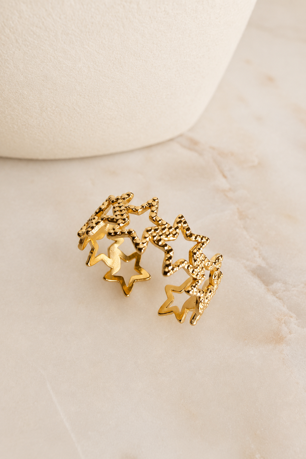 Gold Textured Star Adjustable Ring featuring textured star accents displayed on a marble surface.