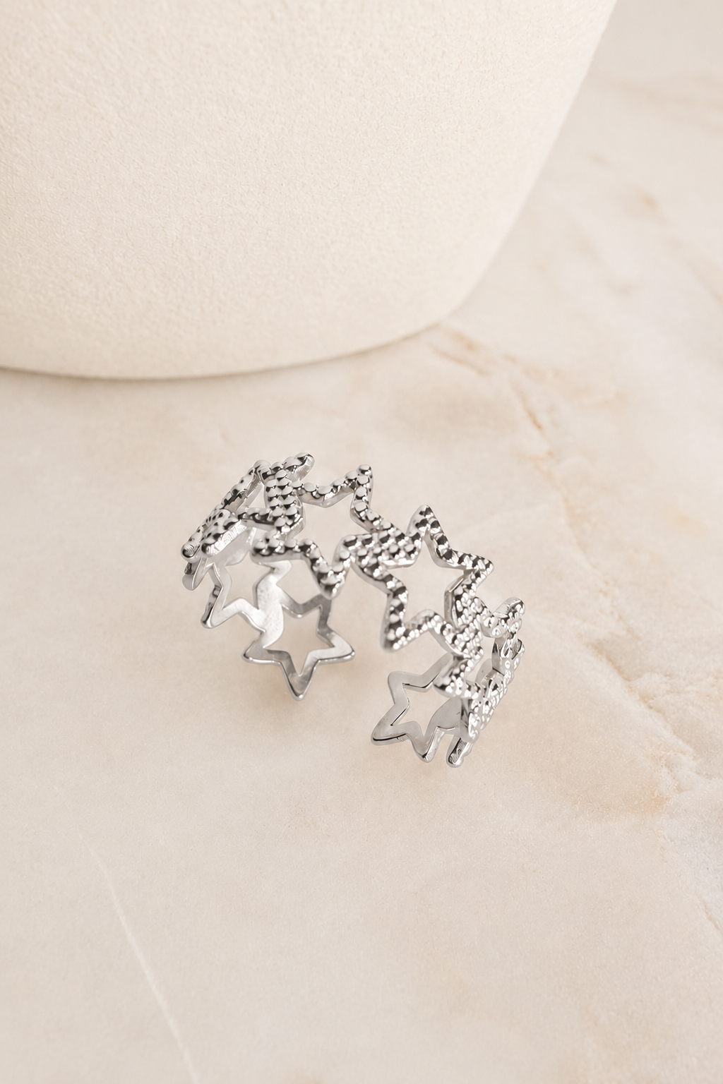Silver Textured Star Adjustable Ring featuring textured star accents displayed on a marble surface.