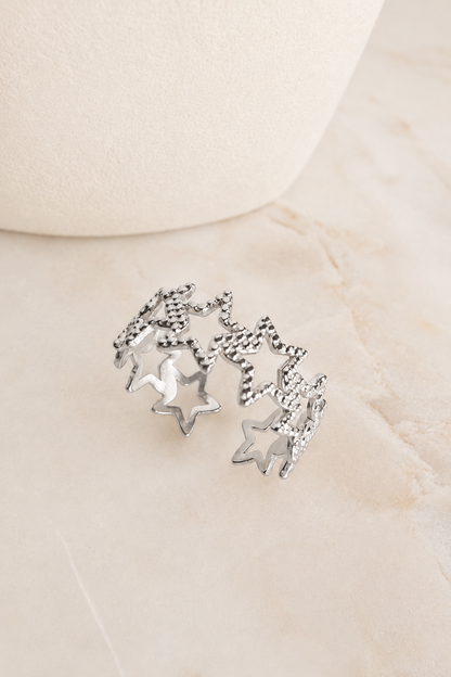 Silver Textured Star Adjustable Ring featuring textured star accents displayed on a marble surface.