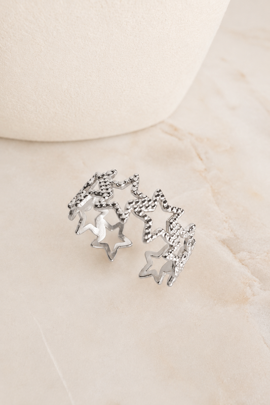 Silver Textured Star Adjustable Ring featuring textured star accents displayed on a marble surface.