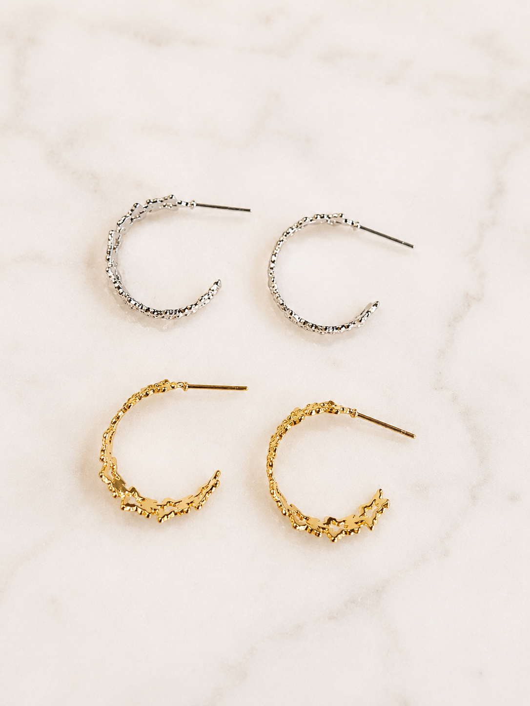 Textured Star Hoops in gold and silver finishes featuring textured star details displayed on a marble surface.