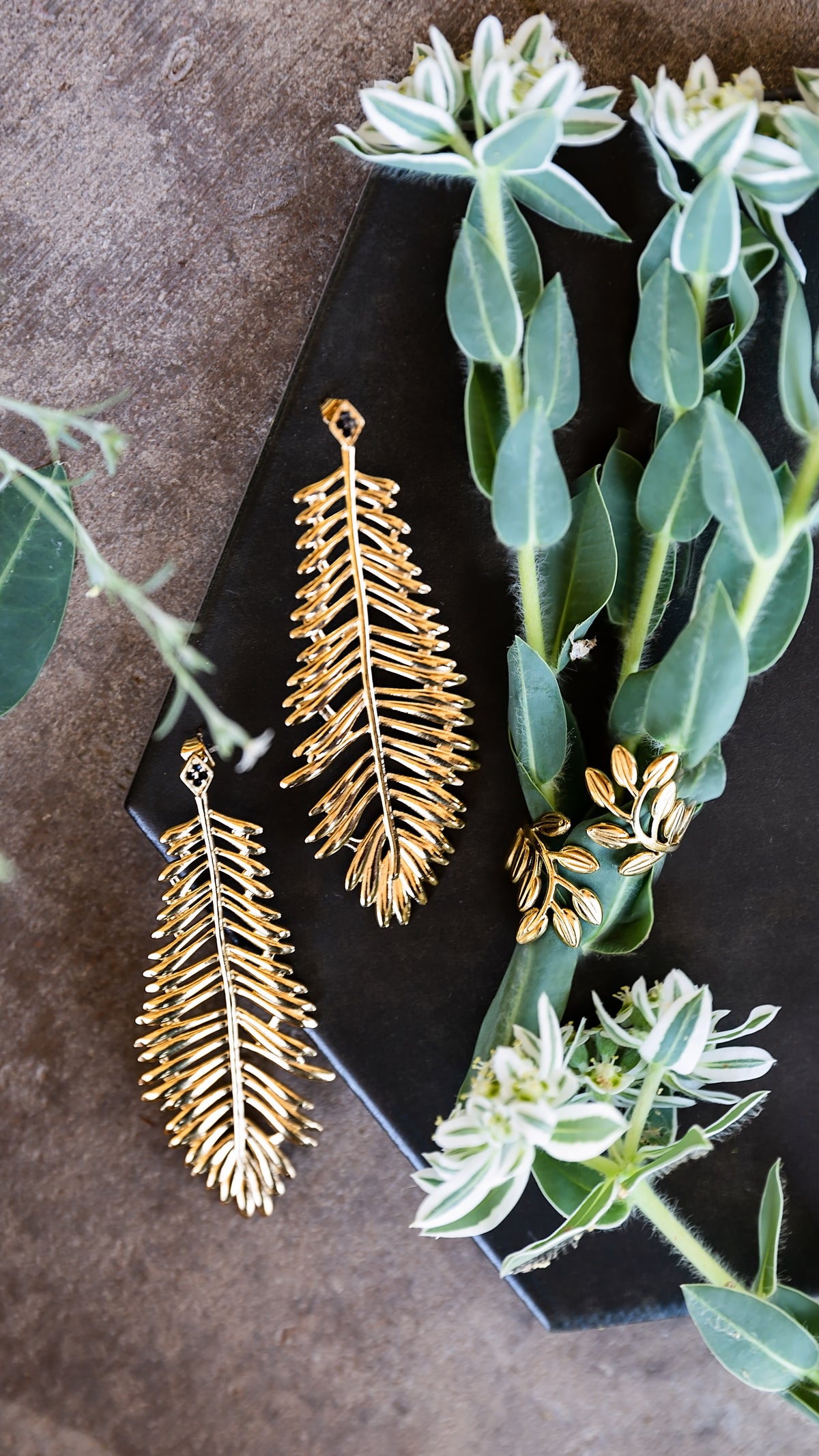 Thalia Earrings styled outdoors, showcasing the dimensional gold leaf design and black crystal accents.