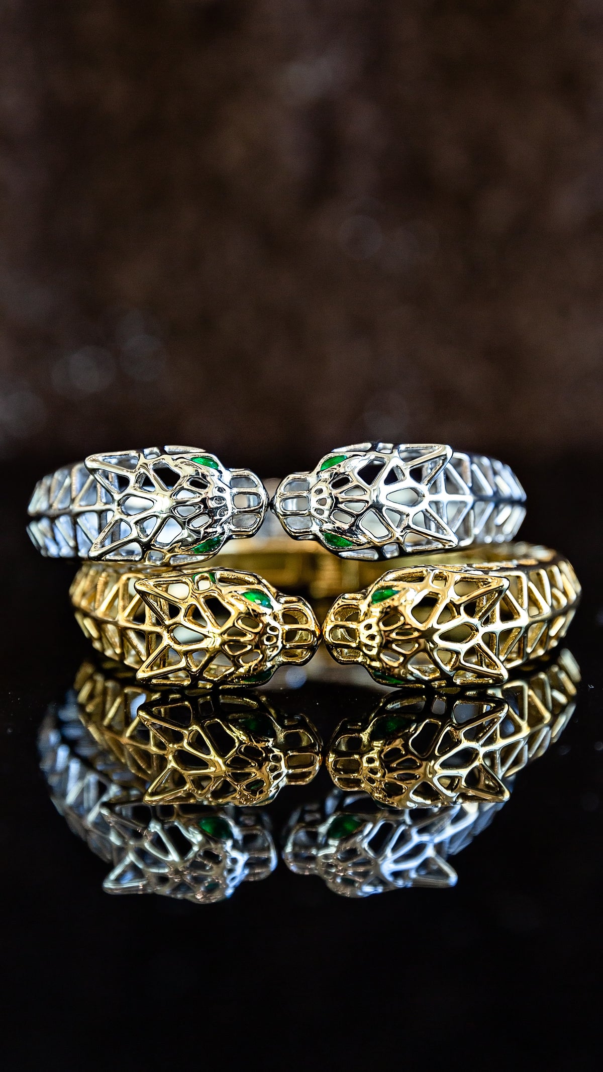 Gold and silver Untamed Cuff bracelets featuring an intricate openwork metal design displayed together on a dark surface.