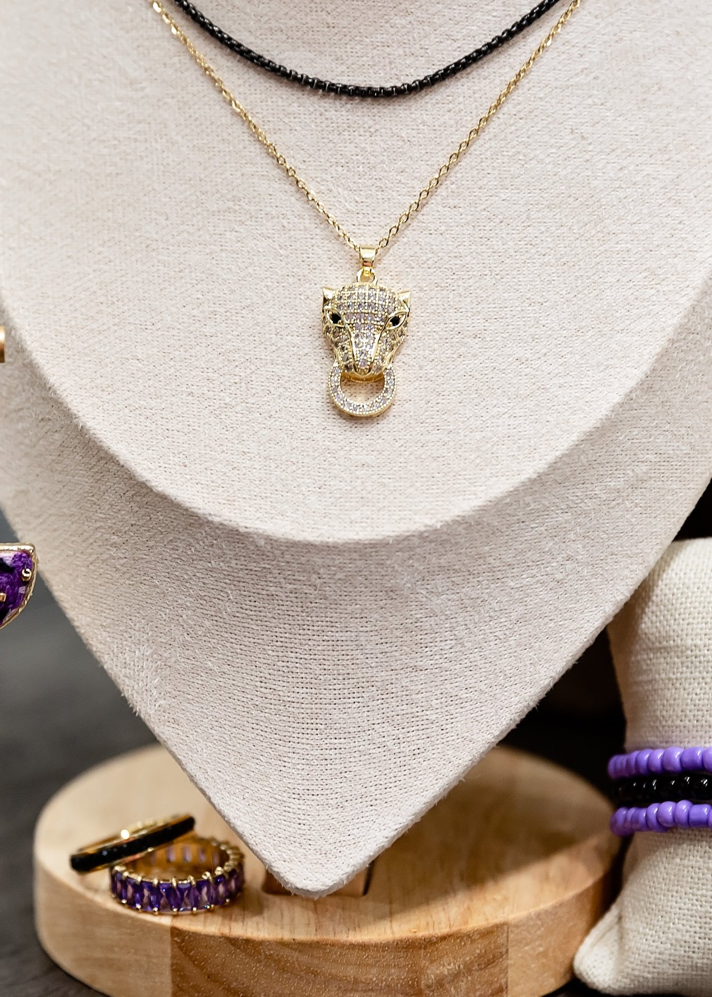 Jewelry set including earrings, necklace, and bracelets on a wooden stand with a neutral background.