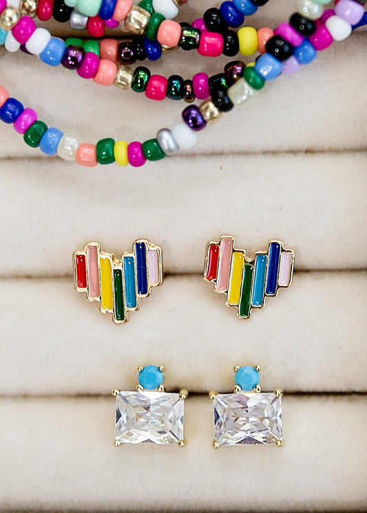 Colorful beaded bracelets and rainbow-stud earrings on a wooden surface