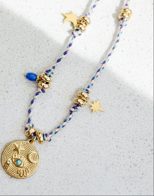 Gold hoop earrings and necklaces with decorative pendants on a textured surface