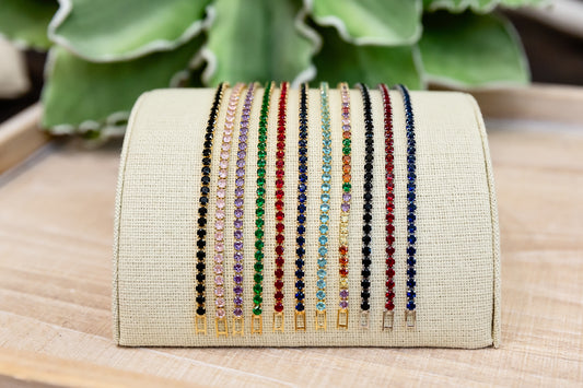 Beige clutch with colorful beaded straps on a wooden surface with green leaves in the background