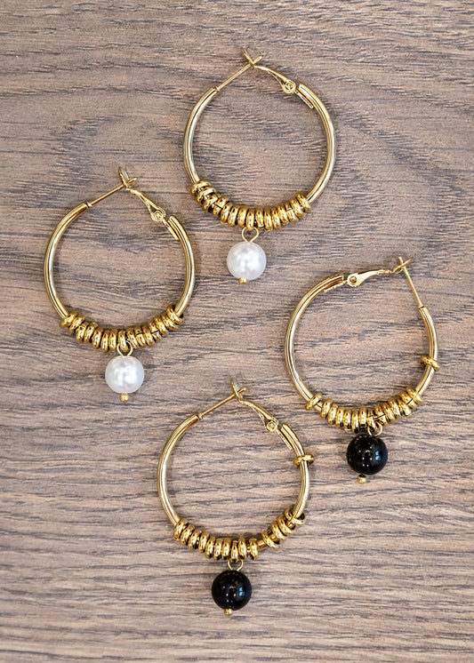 Set of gold hoop earrings with beads on a wooden surface