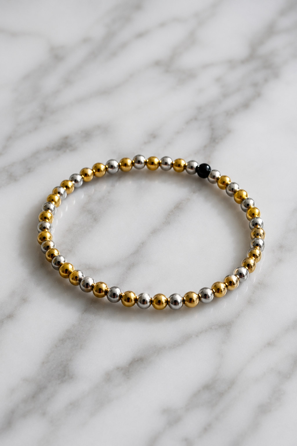 Bracelet with gold and silver beads on a marble background
