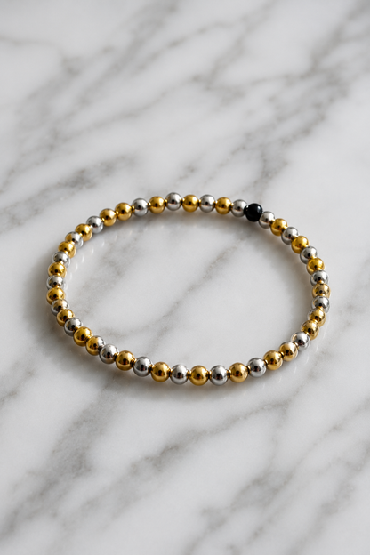 Bracelet with gold and silver beads on a marble background