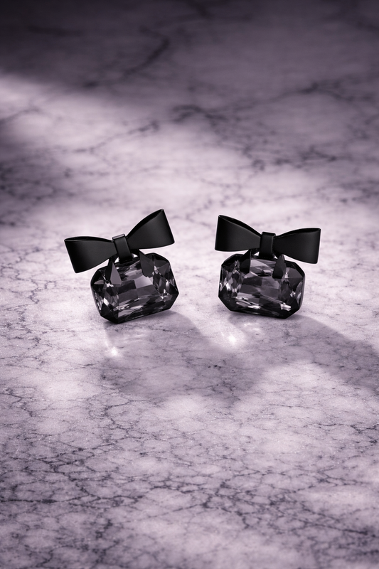 Black bow-tie earrings on a marble surface