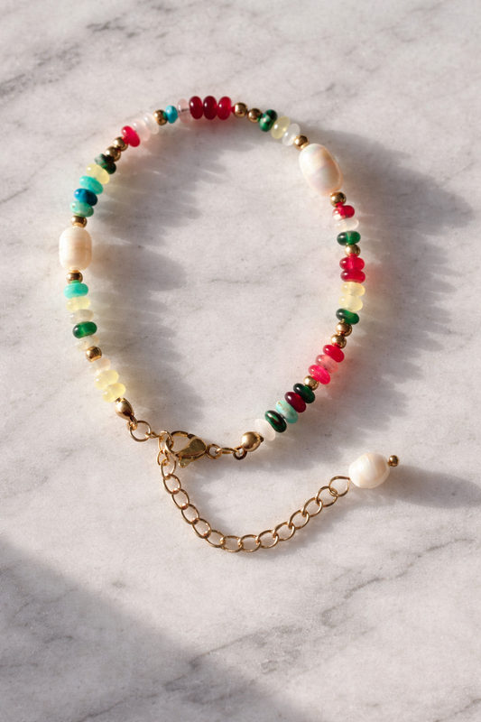 Colorful beaded bracelet with a gold chain on a marble surface