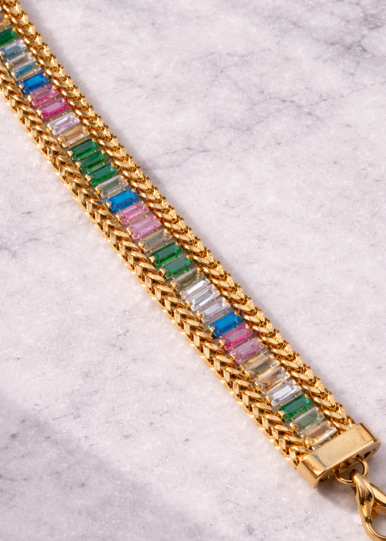 Gold chain bracelet with colorful beads on a marble surface