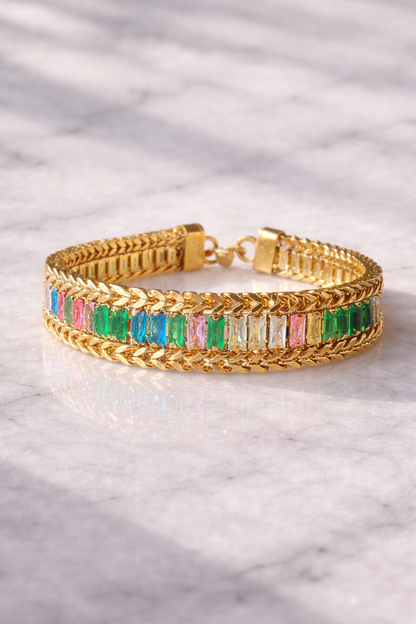 Gold bracelet with colorful gemstones on a marble surface