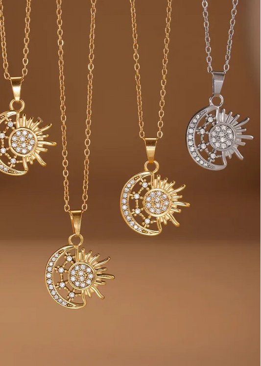 Set of sun and moon pendants on gold and silver chains against a brown background