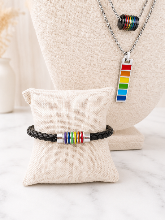 Harvey Barrel Necklace with Pride rainbow pendant styled necklace with a black leather Pride bracelet with rainbow barrel beads on linen jewelry displays