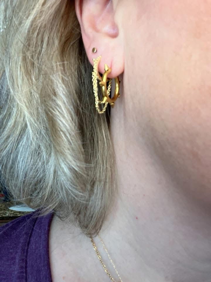 Close-up of ear wearing VEITA Jewelry layered gold hoop earrings with delicate chain necklace
