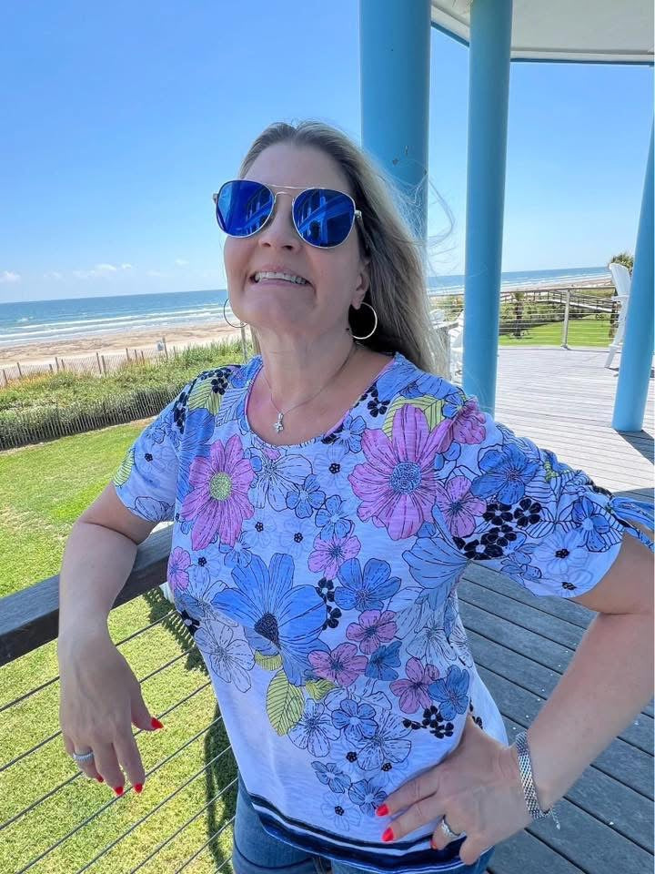 Model wearing VEITA Jewelry gold hoop earrings and delicate charm necklace at the beach