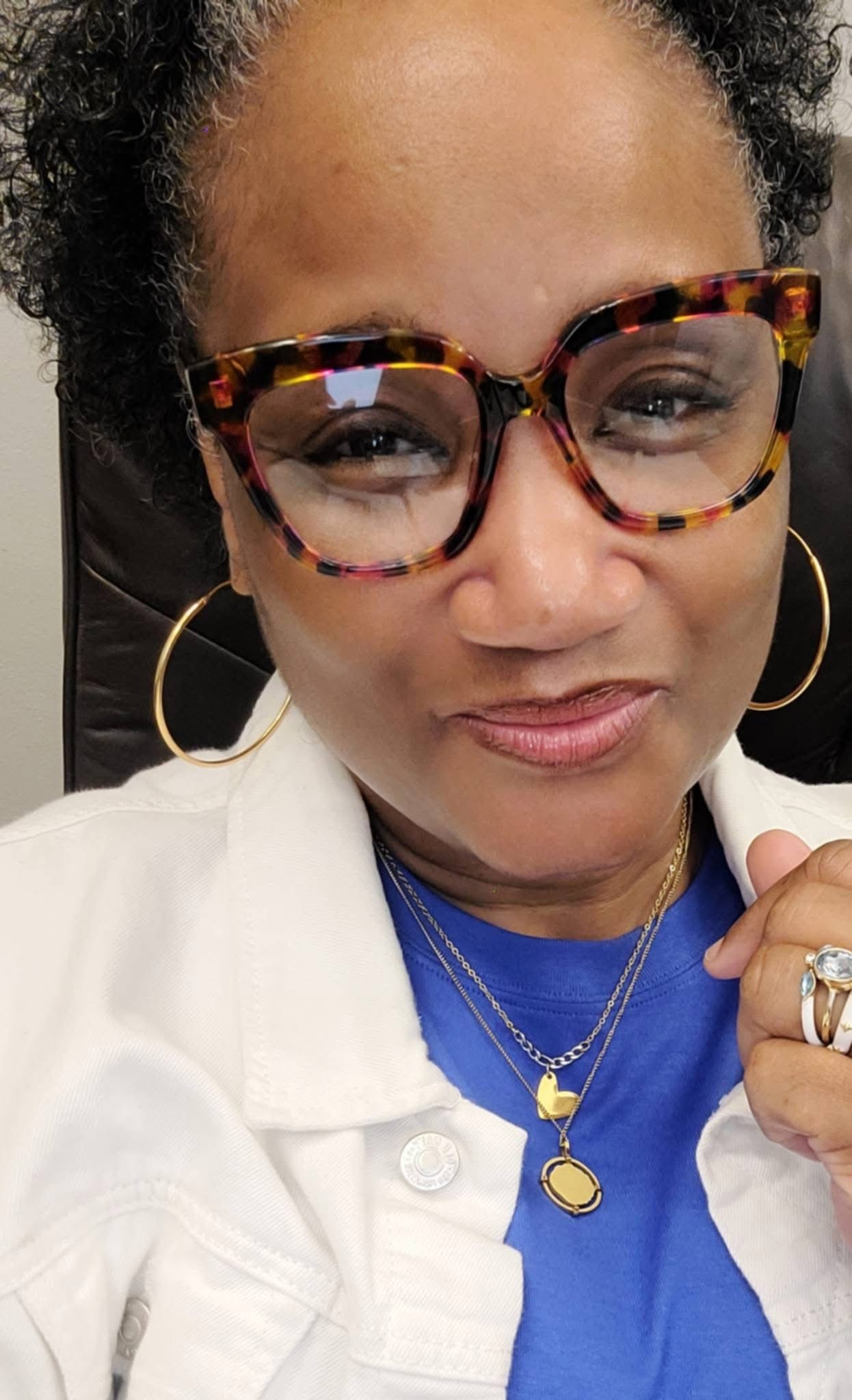 Model wearing VEITA Jewelry large gold hoop earrings and layered gold necklaces with state charm and oval pendant