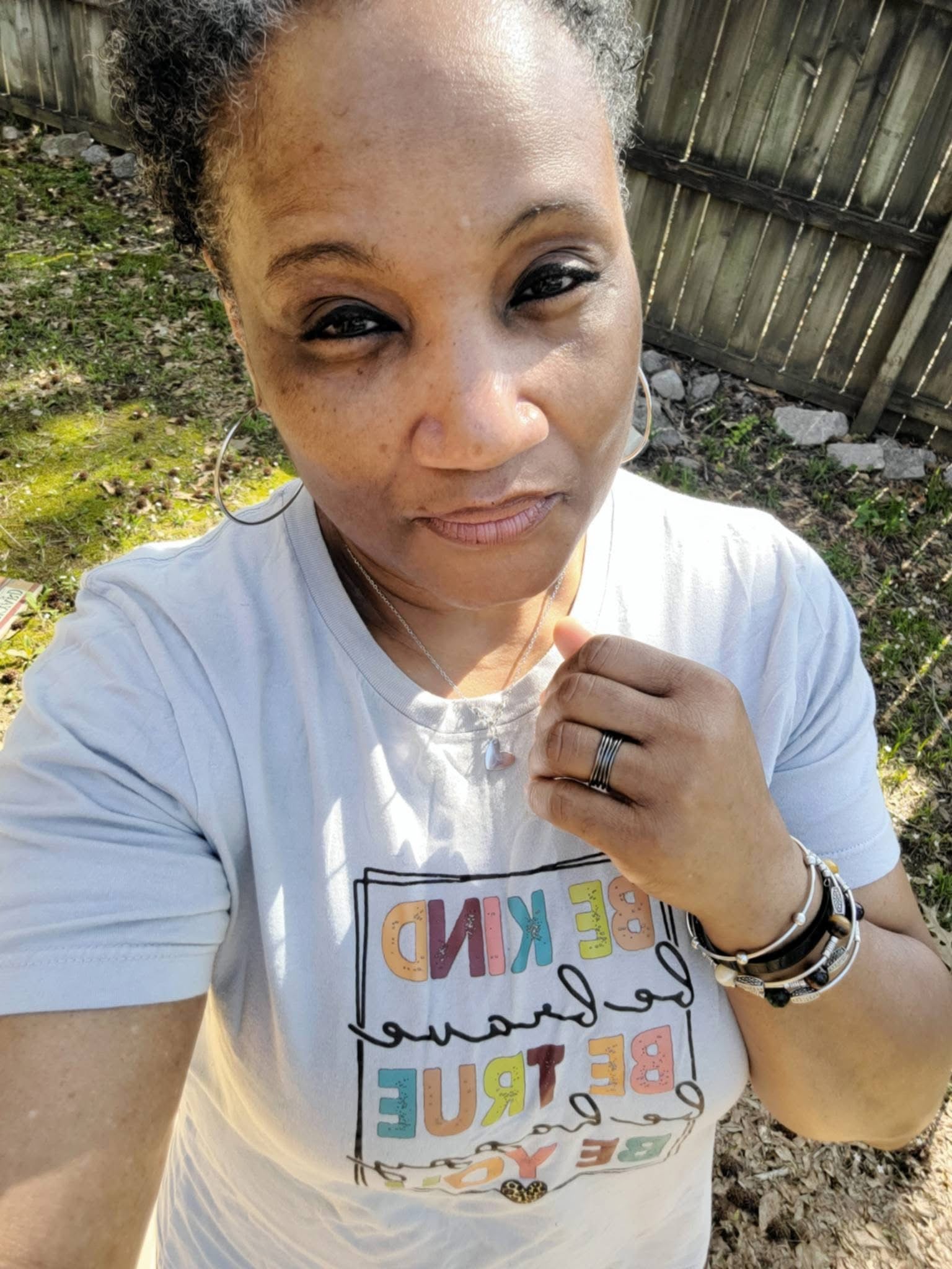 Model wearing VEITA Jewelry large gold hoop earrings, delicate chain necklace with charm, and stacked bracelets