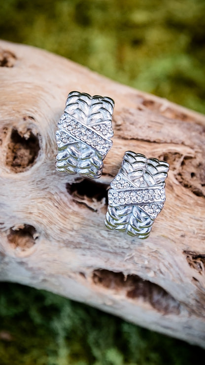 VEITA Jewelry silver chunky woven braided hoop earrings with pavé CZ stones displayed on driftwood with natural background