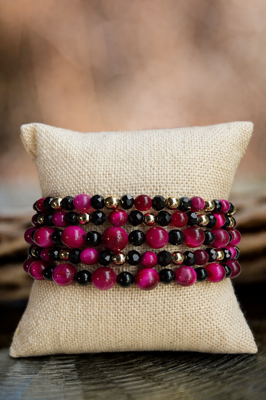 Stack of beaded bracelets on a textured pillow with a blurred natural background